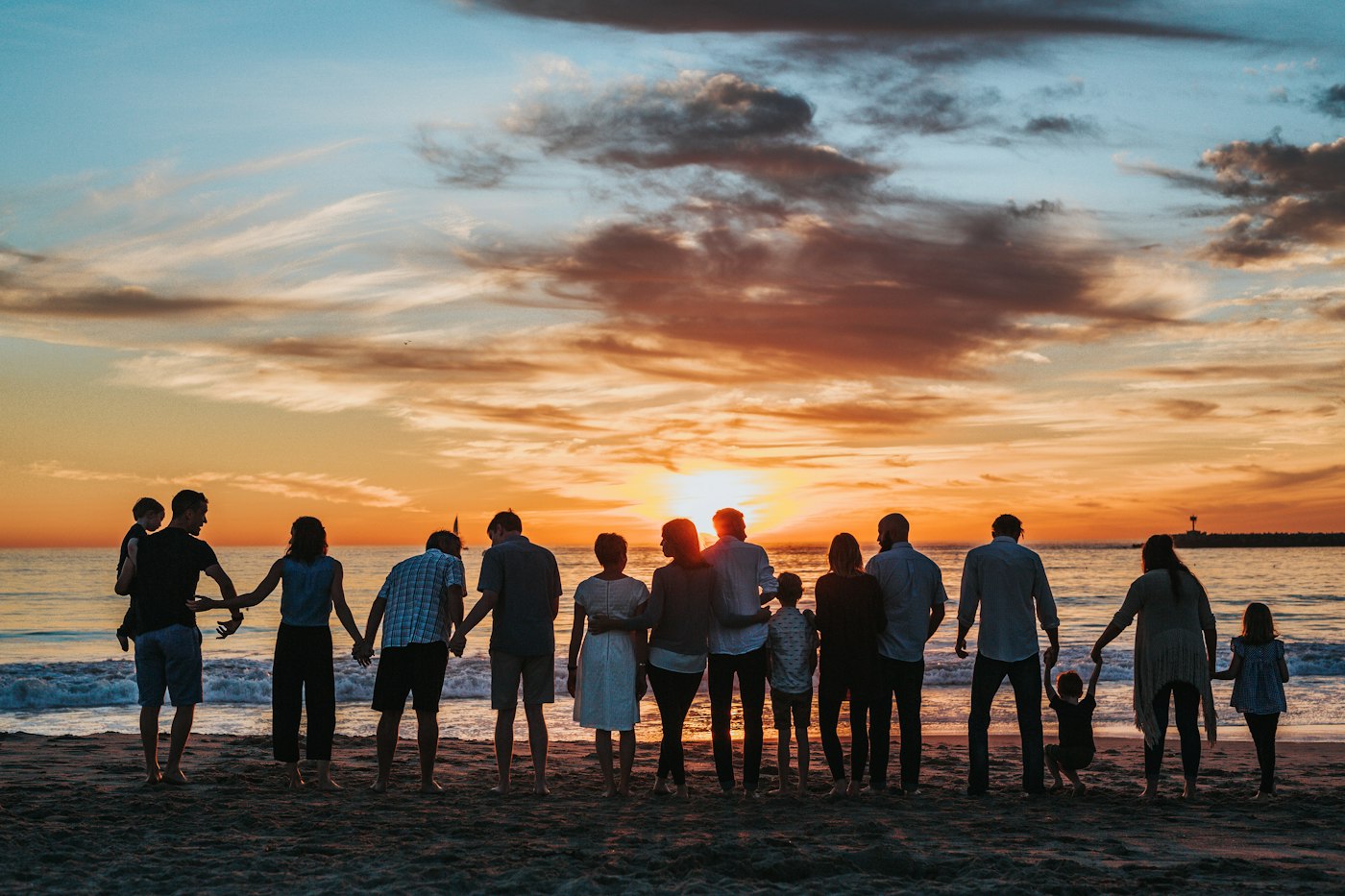 夕日の海辺で手をつなぐ家族